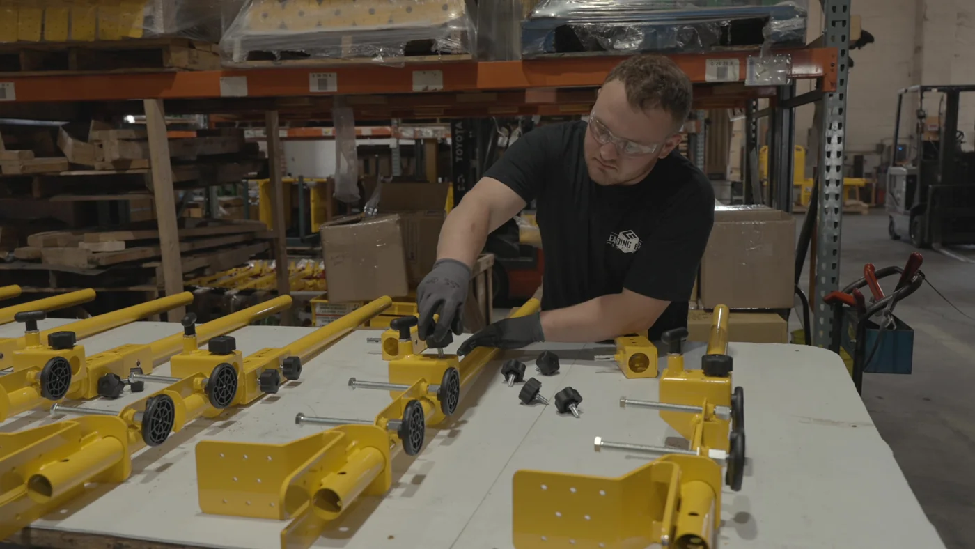 An employee assembling yellow safety product components at a workbench