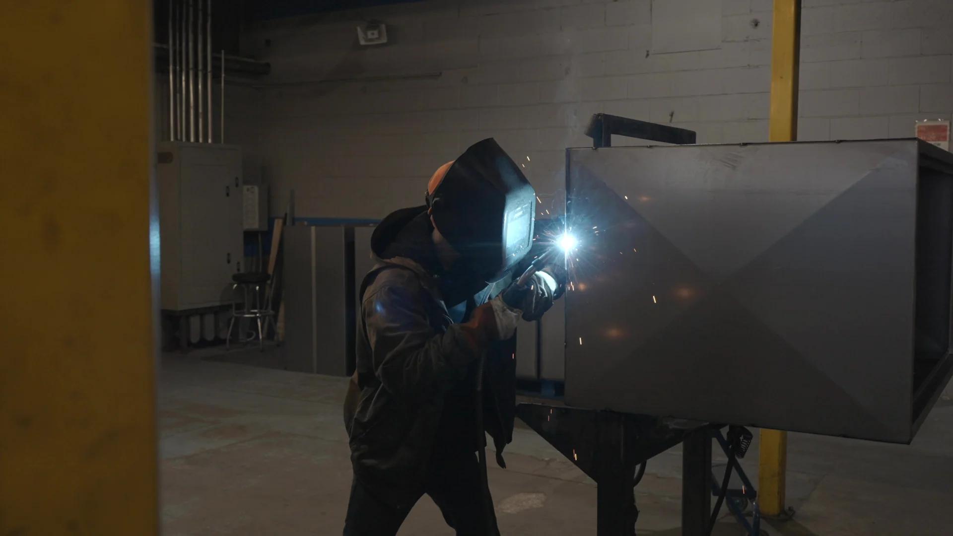AES fabricator welding a large steel assembly, with a bright welding arc