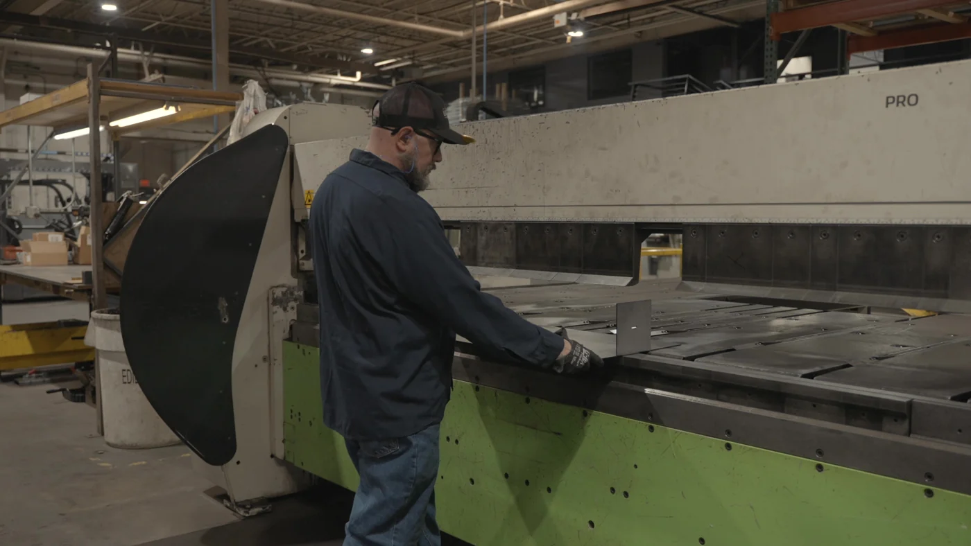 An AES operator positioning sheet metal at a fabrication machine